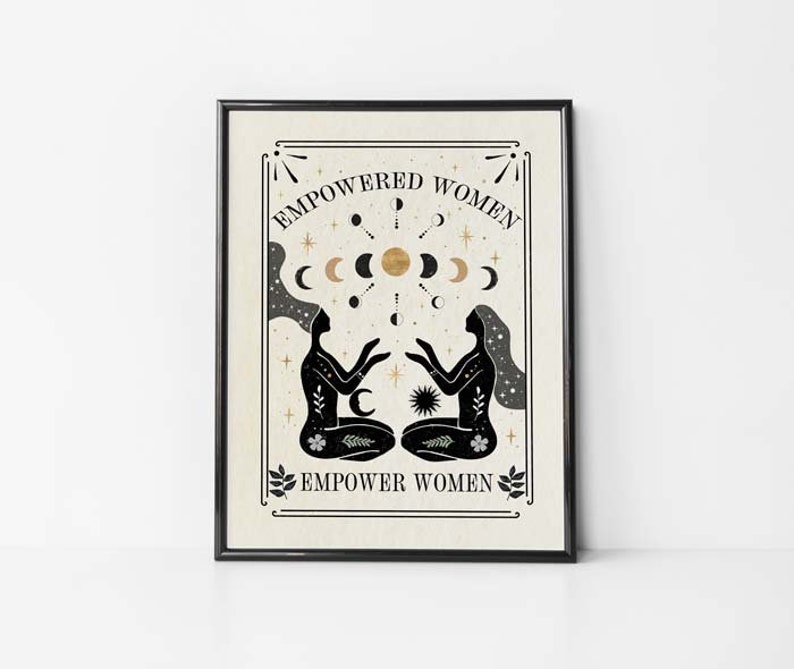May include: Black and white illustration of two women sitting back to back with their hands raised. The women are surrounded by a circle of moons and stars. The text "EMPOWERED WOMEN EMPOWER WOMEN" is printed in black on a beige background.
