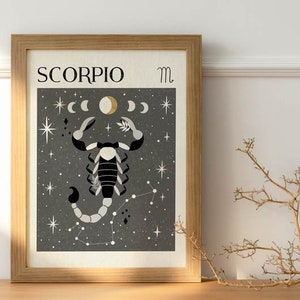 May include: A framed print of a black and white scorpion with a gold moon and stars on a dark gray background. The print has the text "SCORPIO" and the symbol "m" in the top corners.