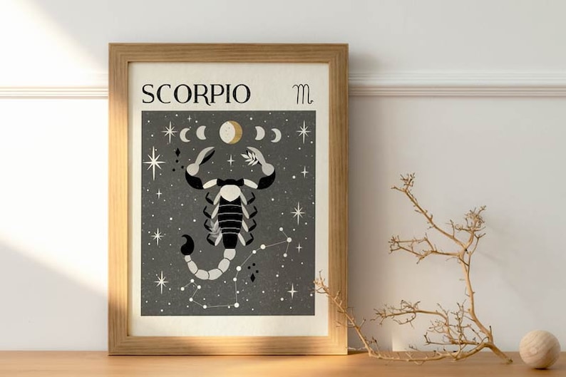 May include: A framed print of a black and white scorpion with a gold moon and stars on a dark gray background. The print has the text "SCORPIO" and the symbol "m" in the top corners.