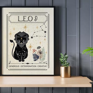 May include: Framed art print featuring a black Leo zodiac illustration. The artwork includes a lion, constellation, and floral elements. The print has the words "LEO" and the traits "GENEROUS, DETERMINATION, CREATIVE".