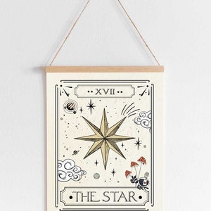 May include: A vintage-style tarot card illustration of The Star card. The card features a large, eight-pointed star in gold with a white outline. The star is surrounded by smaller stars, clouds, and a planet. The card is framed in a black border with the Roman numeral XVII and the text "THE STAR" in black.