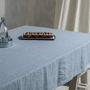 May include: A light blue linen tablecloth with a silver metal serving tray holding a baked pastry on a wooden table.