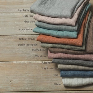 May include: A stack of 12 linen fabric swatches in various colors, including light grey, pale rose, grey blue, aquamarine, natural orange, desert sage green, mocha brown, woodrose, graphite, light natural, blue, and white.