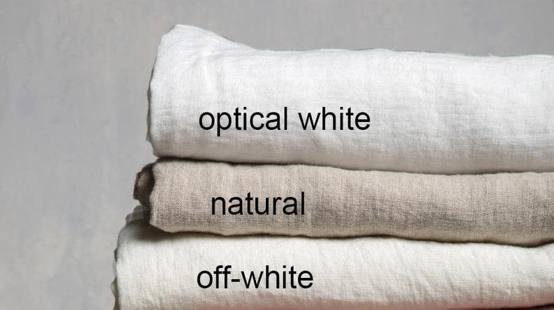 May include: Three linen fabric swatches stacked on top of each other. The top swatch is optical white, the middle swatch is natural, and the bottom swatch is off-white.