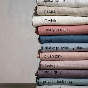 Puede incluir: Un conjunto de muestras de tejido de lino en varios tonos de gris, rosa, azul y blanco. Las muestras est&aacute;n etiquetadas con sus nombres de color, incluyendo "blanco &oacute;ptico", "natural", "blanco roto", "rosa ca&ntilde;&oacute;n", "azul", "gris azulado/azul polvoriento", "rosa rubor", "rosa polvoriento", "gris morado", "huevo de pato gris&aacute;ceo", "gris claro/gris plateado" y "gris oscuro".