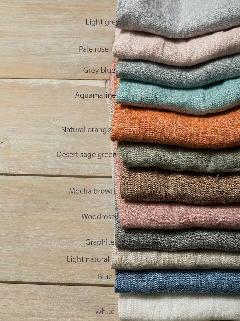May include: A stack of 12 fabric swatches in various colors, including light grey, pale rose, grey blue, aquamarine, natural orange, desert sage green, mocha brown, woodrose, graphite, light natural, blue, and white.