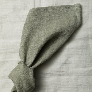 May include: A green linen napkin with a herringbone pattern, folded and tied into a knot.