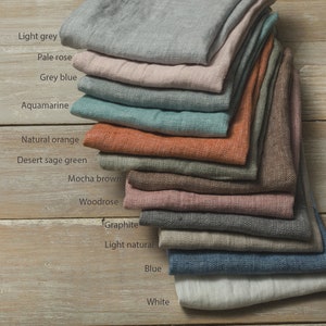 May include: A stack of 12 linen fabric swatches in various colours, including light grey, pale rose, grey blue, aquamarine, natural orange, desert sage green, mocha brown, woodrose, graphite, light natural, blue, and white.