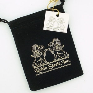 K&ouml;nnte beinhalten: Eine schwarze Samt-Zugschnur-Tasche mit einem goldenen Logo, das "Robin Steele, Inc." lautet und zwei stilisierte Greife zeigt. Die Tasche wird von einem wei&szlig;en Etikett mit dem gleichen Logo begleitet.