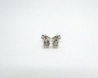 May include: A pair of silver stud earrings with small, clear round gemstones.