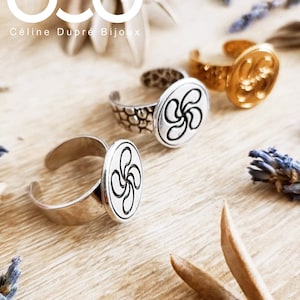 Peut inclure: Anneaux en argent avec un motif de croix basque. Collection « Lauburu / Croix Basque ». Les bagues mesurent 17 mm de diamètre. Présentées sur une surface en bois clair. Fabriqué en France.