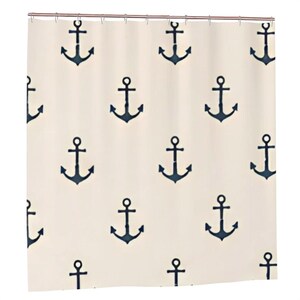 May include: A shower curtain featuring a repeating pattern of dark navy blue nautical anchors printed on a solid off-white background. The curtain is suspended from a horizontal rod with visible metal rings along the top edge of the fabric.
