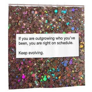 May include: A shower curtain featuring a dark brown background covered in multicolored, reflective hexagonal glitter. A white rectangular panel in the center displays the black text: If you are outgrowing who you’ve been, you are right on schedule. Keep evolving.