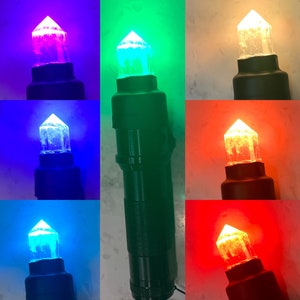 May include: A close-up of six crystal wands with different colored lights. The wands are black with a clear crystal on top. The lights are red, orange, yellow, green, blue, and purple.