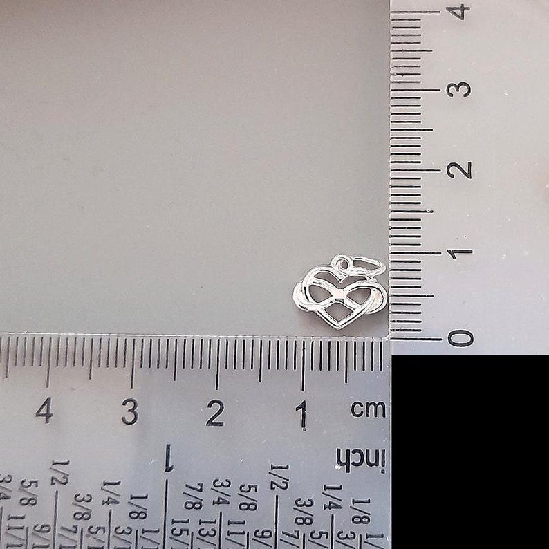 May include: Silver charm in the shape of an infinity symbol intertwined with a heart. The charm is approximately 1 inch in length.