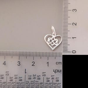 May include: A silver Celtic knot heart charm pendant measuring approximately 2.5 cm in length. The charm is in the shape of a heart with a Celtic knot design inside.