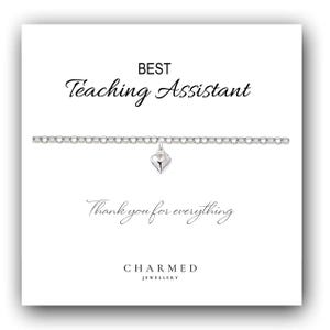 Könnte beinhalten: Ein silbernes Armband mit Herzanhänger, präsentiert auf einer weißen Karte. Auf der Karte steht „BEST Teaching Assistant“ und „Thank you for everything“. Der Markenname „CHARMED JEWELLERY“ ist zu sehen.