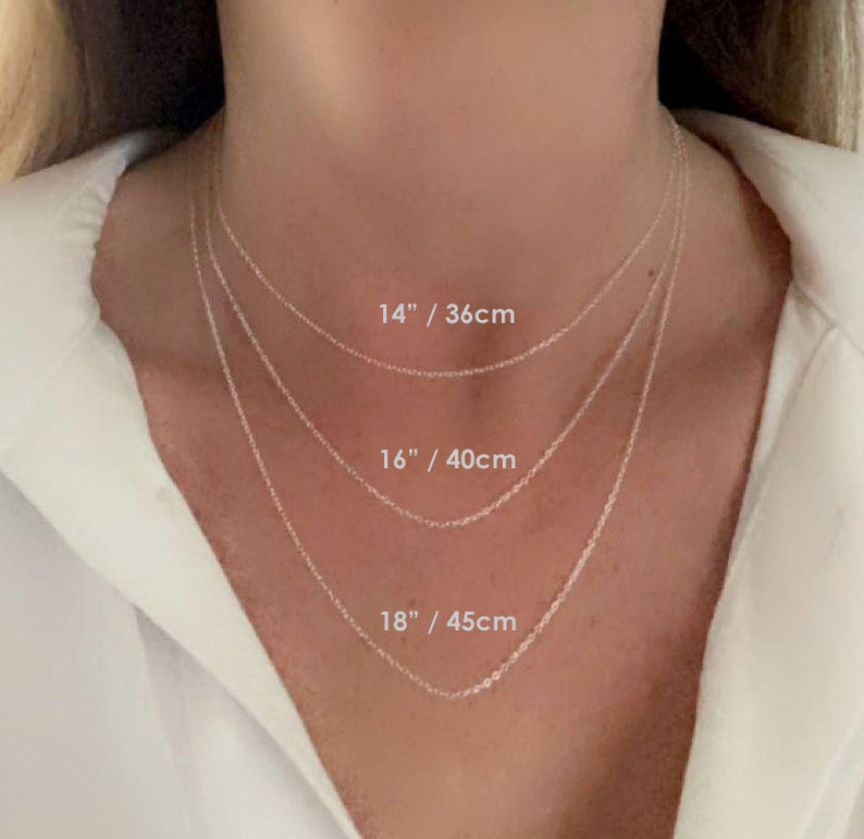 May include: Three silver chains of different lengths, 14 inches, 16 inches, and 18 inches, are shown on a model's neck. The lengths are labeled in inches and centimeters.