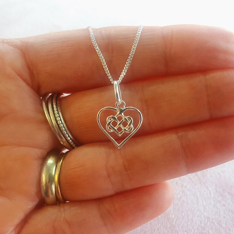 May include: A silver necklace featuring a Celtic knot heart pendant. The pendant is a delicate, intricate design.