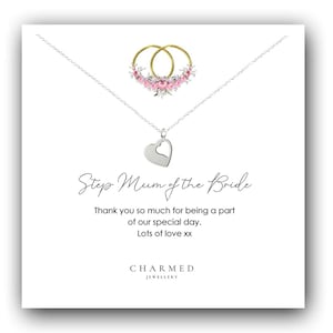 Puede incluir: Un collar de plata con un colgante de corazón y un dije de anillo con flores rosas. La tarjeta dice "Step Mum of the Bride" e incluye el mensaje "Thank you so much for being a part of our special day. Lots of love xx" y el nombre de la marca "CHARMED JEWELLERY".