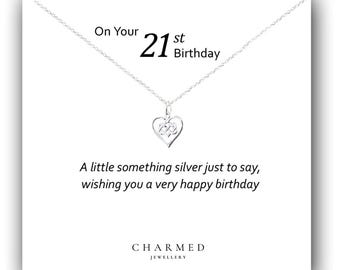 Op de afbeelding: Een zilveren ketting met een hartvormige hanger op een witte kaart met de tekst "On Your 21st Birthday" en "A little something silver just to say, wishing you a very happy birthday". De kaart heeft ook de tekst "CHARMED JEWELLERY".