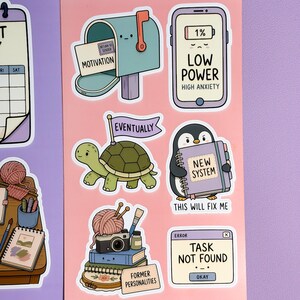 May include: A sticker sheet on a peach background featuring cartoon illustrations: a mailbox labelled 'Motivation', a phone showing 'Low Power', a turtle with an 'Eventually' flag, a penguin holding a 'New System' book, a stack of items labelled 'Former Personalities', and a computer window reading 'Task Not Found'.