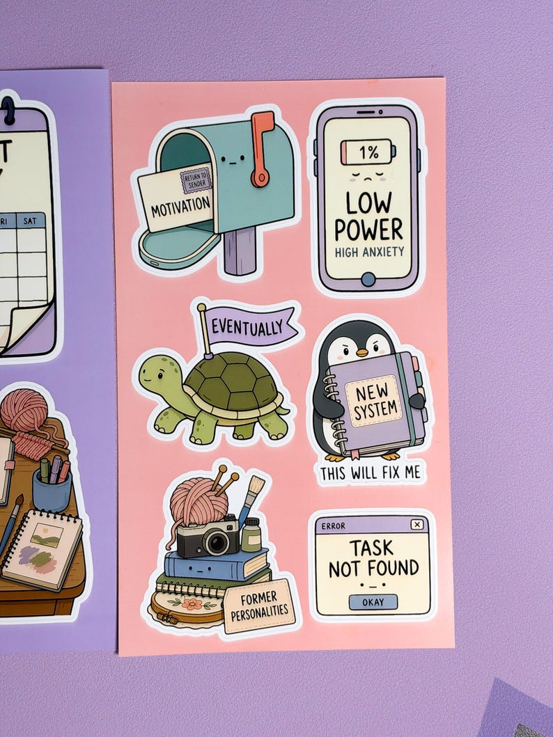 May include: A sticker sheet on a peach background featuring cartoon illustrations: a mailbox labelled 'Motivation', a phone showing 'Low Power', a turtle with an 'Eventually' flag, a penguin holding a 'New System' book, a stack of items labelled 'Former Personalities', and a computer window reading 'Task Not Found'.