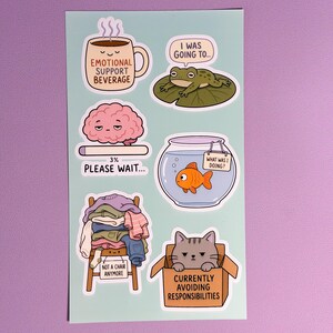 May include: A light blue sticker sheet featuring six illustrations: a coffee mug labelled "Emotional Support Beverage," a frog on a lily pad, a brain with a "3% Please Wait" loading bar, a goldfish in a bowl, a chair piled with clothes, and a cat in a box.