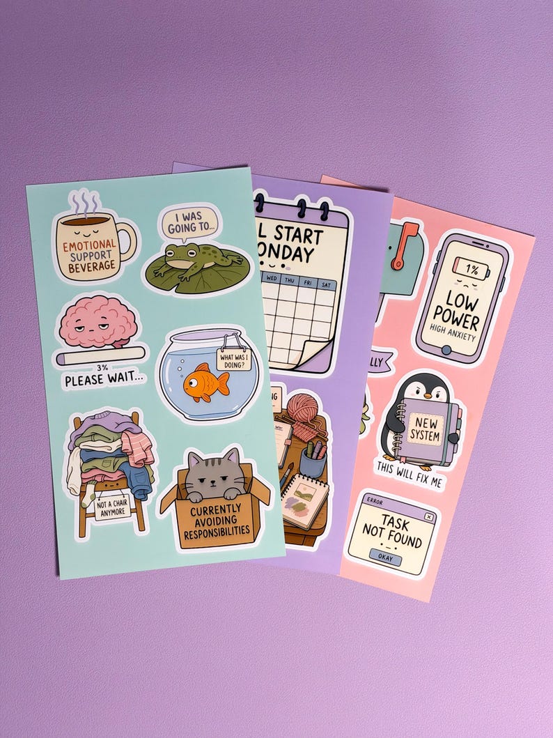 May include: Three sticker sheets featuring various illustrations and text. The light blue sheet includes a coffee mug, a frog, a brain, a goldfish bowl, a pile of clothes, and a cat in a box. The purple and pink sheets feature a calendar, a phone, a penguin, and computer error messages.