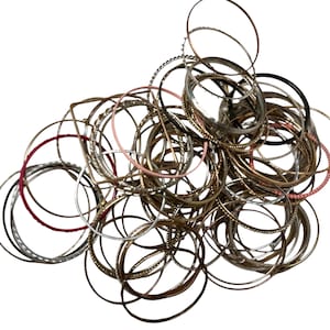 May include: A collection of assorted bangles in various colors and designs. The bangles are made of metal and feature different textures, including smooth, beaded, and textured surfaces. Colors include silver, gold, black, pink, and red.