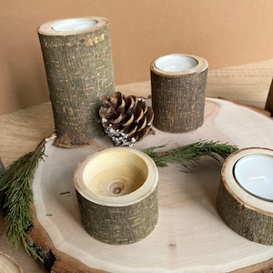 May include: A wooden candle holder set with four individual holders, each made from a tree branch with the bark still on. The holders are arranged on a wooden slice with a pine cone in the center.