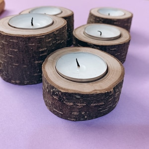 May include: Five wooden candle holders with white tea lights. The holders are made from tree bark and have a natural wood finish.