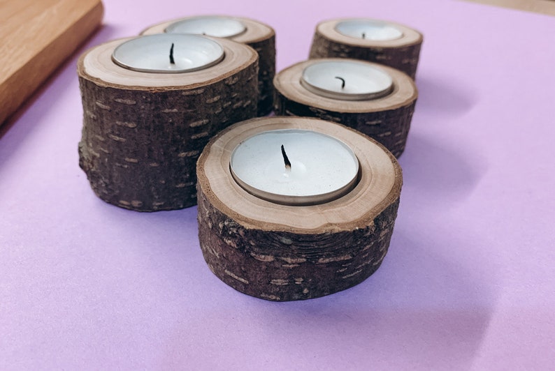 May include: Five wooden candle holders with white tea lights. The holders are made from tree bark and have a natural wood finish.