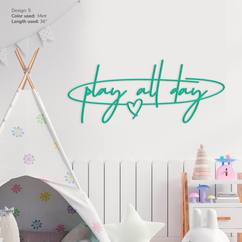 May include: A mint green metal wall decor with the text "play all day" in a cursive font. A small heart is included in the design.