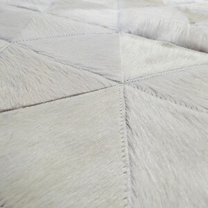 Close up of a White Triangles Patchwork Cowhide Rug. The Kata cowhide area rug in cream, off-white hide. Available in custom and standard siezes 8x10ft, 9x12ft, 10x13ft. Free shipping to USA and Canada
