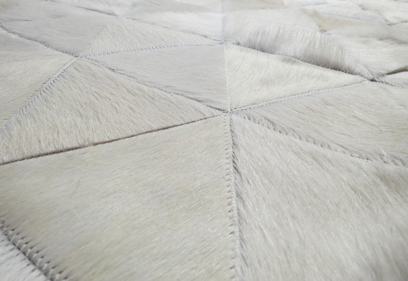Close up of a White Triangles Patchwork Cowhide Rug. The Kata cowhide area rug in cream, off-white hide. Available in custom and standard siezes 8x10ft, 9x12ft, 10x13ft. Free shipping to USA and Canada