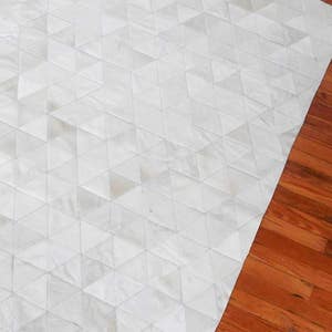White Triangles Patchwork Cowhide Rug on wooden floor. The Kata cowhide area rug in cream, off-white hide. Available in custom and standard siezes 8x10ft, 9x12ft, 10x13ft. Free shipping to USA and Canada