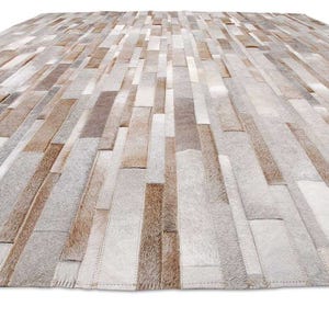 Floor view of a Taupe, Beige, Gray Stripes Patchwork Cowhide Rug.