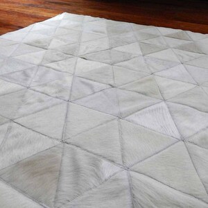 Detail of a White Triangles Patchwork Cowhide Rug. The Kata cowhide area rug in cream, off-white hide. Available in custom and standard siezes 8x10ft, 9x12ft, 10x13ft. Free shipping to USA and Canada