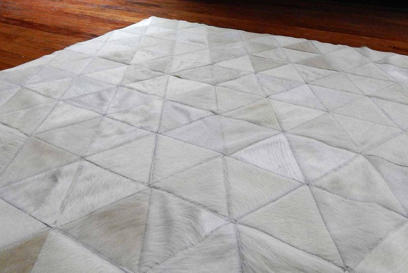 Detail of a White Triangles Patchwork Cowhide Rug. The Kata cowhide area rug in cream, off-white hide. Available in custom and standard siezes 8x10ft, 9x12ft, 10x13ft. Free shipping to USA and Canada