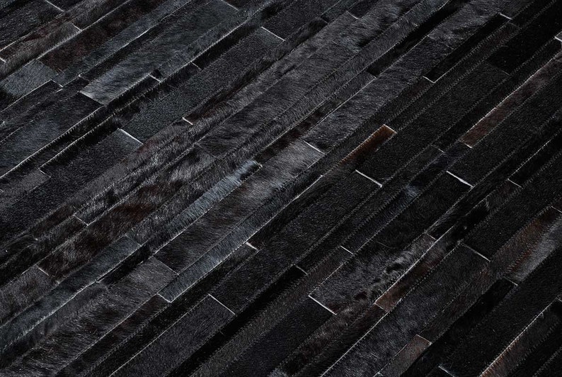 Detail of a Black Stripes Patchwork Cowhide Rug by Shine Rugs. A cowhide rug suitable for any kind of home decor. Bright and shiny natural black hair. Custom sizes, free shipping to US and Canada.