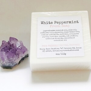 May include: A white bar of "White Peppermint Fresh Soap" with a label listing ingredients. Next to the soap is a cluster of purple amethyst crystals. The soap is 4oz/113g.