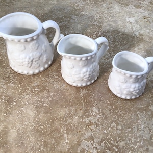 White ceramic fruit design measuring pitchers, vintage, ships from Canada