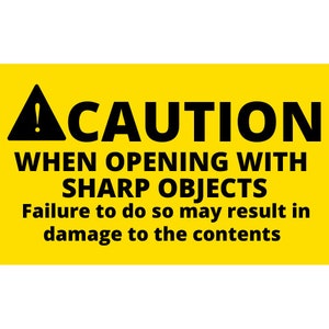 Puede incluir: Un letrero rectangular amarillo con texto negro. El letrero dice "CAUTION" encima del texto "WHEN OPENING WITH SHARP OBJECTS". Debajo, dice "Failure to do so may result in damage to the contents."