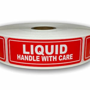 May include: A roll of white labels with a red rectangular border. The labels read "LIQUID HANDLE WITH CARE" in bold white text. The roll is on a white background.