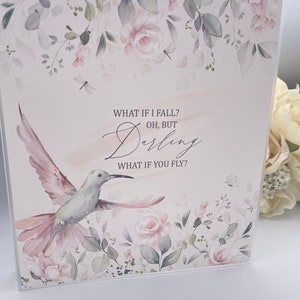 May include: A watercolor print with a hummingbird in flight, surrounded by pink flowers and green leaves. The print features the text "What if I fall? Oh, but Darling, What if you fly?"
