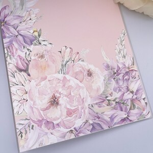 Peut inclure: Une carte rose avec un motif floral aquarelle représentant des fleurs violettes et blanches. Les fleurs sont disposées dans un coin de la carte, le reste de la carte étant d'un rose uni.