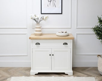 Aparador pequeño con cajón sobre puertas dobles y tablero rústico grueso. Base pintada de blanco con tablero de madera maciza de pino. Personalizable.
