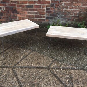 May include: Two whitewashed wooden coffee tables with hairpin legs. The larger table is in the background and the smaller table is in the foreground.