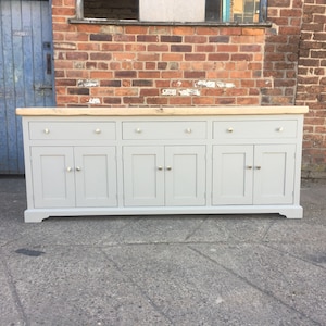 Op de afbeelding: Een grijs geverfde houten dressoir met zes deuren en vier lades. De bovenkant van het dressoir is gemaakt van natuurlijk hout.